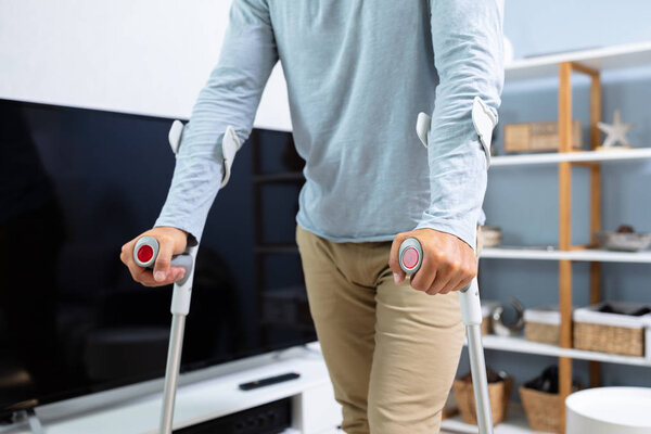 Инвалид, использующий костыли, чтобы ходить по дому
