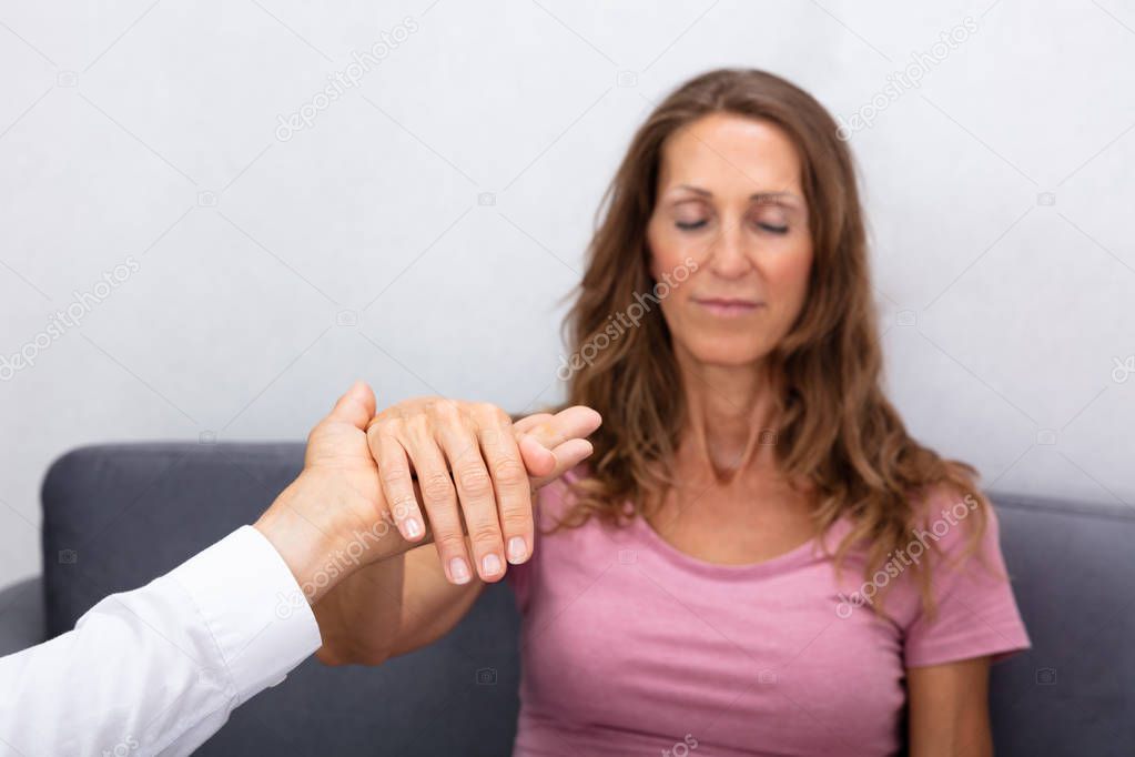 Close-up Of Professional Hypnotherapist Holding Woman Hand During Hypnotherapy