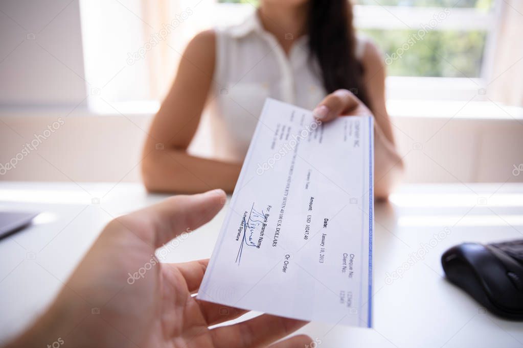 Close-up Of A Businesswoman's Hand Giving Cheque To Colleague