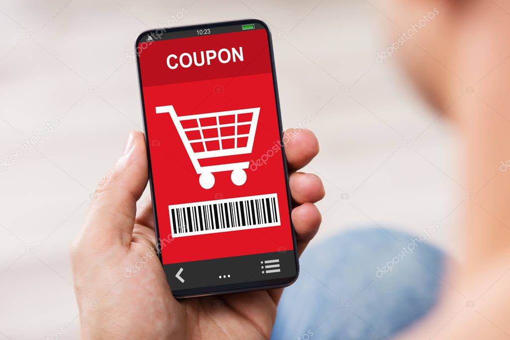 Close-up Of Man's Hand Holding Mobile Phone With Shopping Coupon