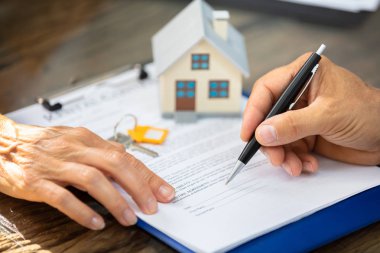 Bir Emlakçının Elinin Masa Üstü Sözleşme Formunu Doldurmasında Müşteriye Yardım Etme