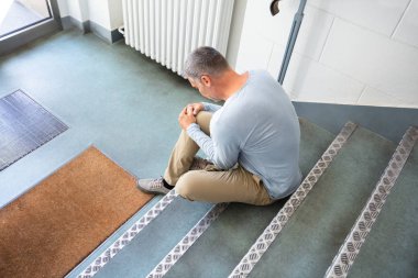 kayma ve düşme kazasından sonra merdivenlerde oturan olgun adam