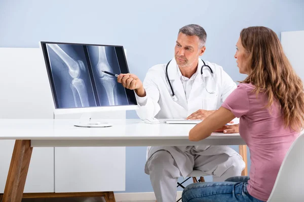 医生在电脑屏幕上向病人显示膝部X光片 — 图库照片
