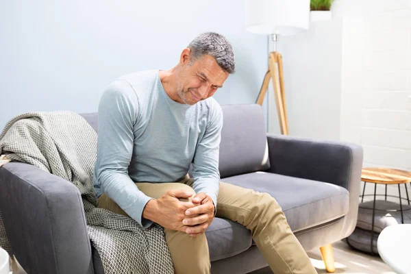 Mann Mit Knieschmerzen Sitzt Auf Sofa — Stockfoto