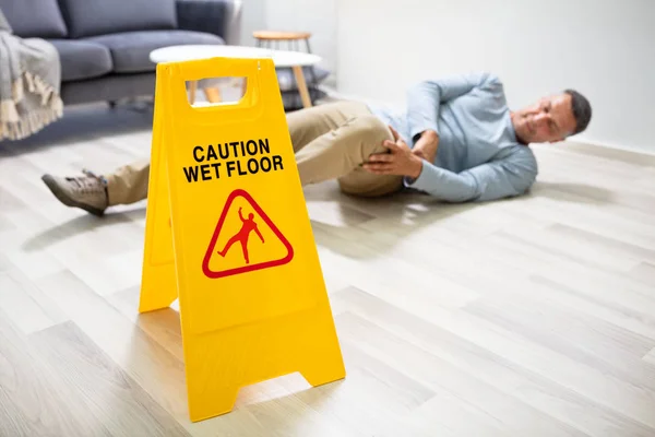 Volwassen Man Vallen Natte Vloer Voorkant Van Waarschuwing Teken Thuis — Stockfoto