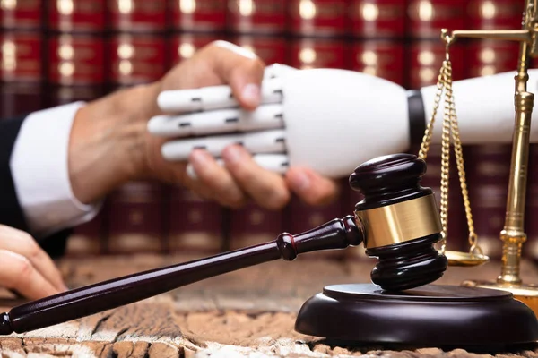 Robot Shaking Hands With Judge Near Gavel On Wooden Desk