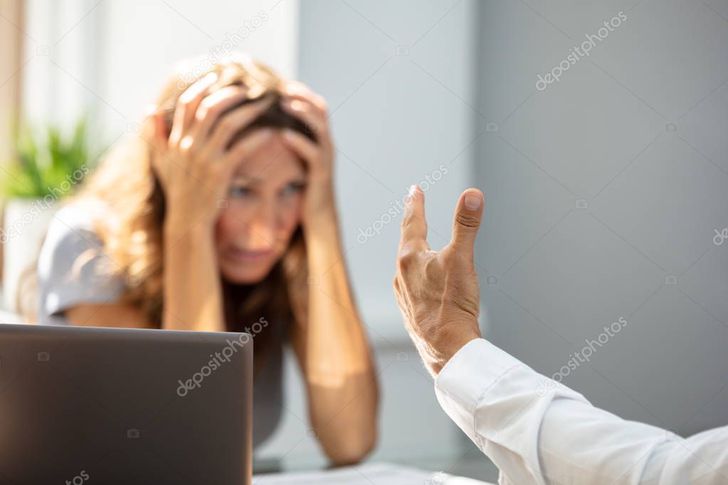 Unhappy Woman Looking At Her Colleague While Sitting In Office