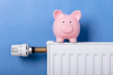 Piggy Bank Mavi Arka Plan Karşı Sıcaklık Regülatörü ile Isıtma Radyatörü On