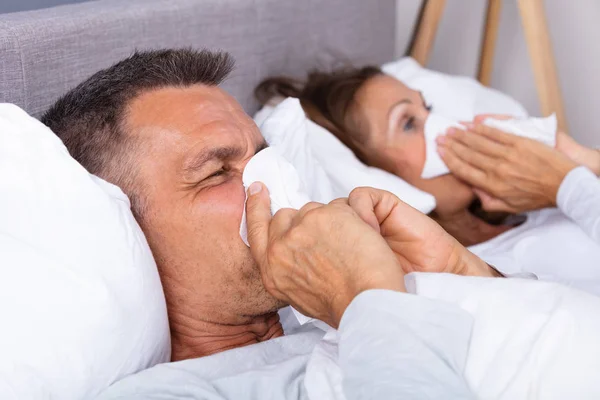 Sick Mature Couple Lying Bed Blowing Nose Bedroom — Stock Photo, Image