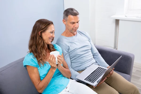 快乐成熟的夫妇坐在Sofa看电影在笔记本电脑在家里 — 图库照片