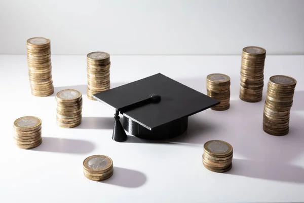 Chapéu Preto Graduação Com Empilhamento Dourado Das Moedas Fundo Branco — Fotografia de Stock