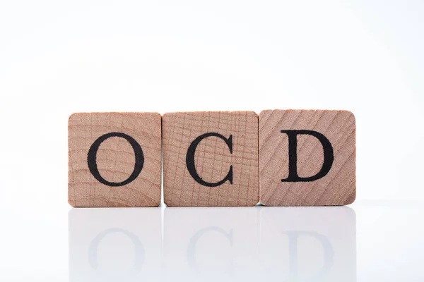 stock image Close-up Of Ocd Text On Wooden Block Over Reflective Desk