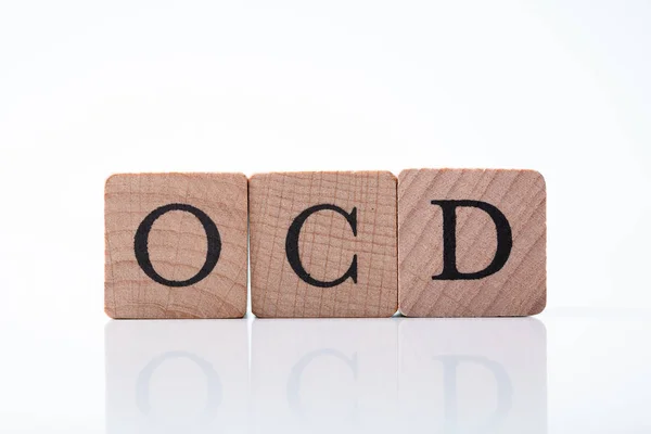 Stock image Close-up Of Ocd Text On Wooden Block Over Reflective Desk