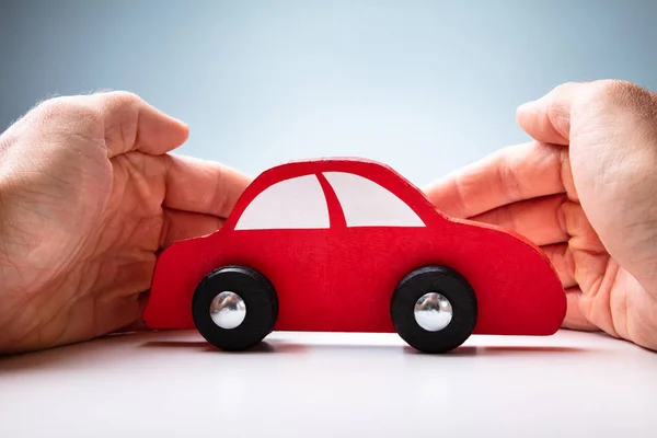 Mão Empresário Que Protege Carro Vermelho Brinquedo Mesa Madeira — Fotografia de Stock