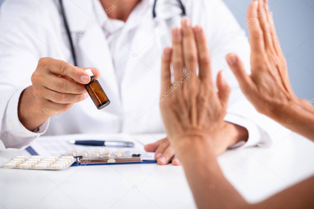 Close-up Of A Person's Hand Refusing To Use Medication Held By Doctor