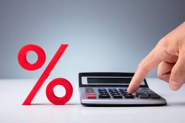 Beyaz Masa Üzerinde Kırmızı Yüzde İşaretinin Yanında Hesap Makinesi Kullanan Kişinin Eli