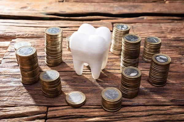 木製の机の上に白い健康な人間の歯と積み重ねられたコイン — ストック写真