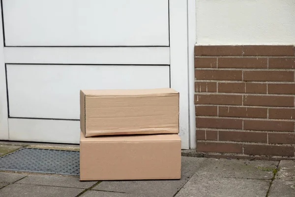 Stack Of Brown Cardboard Boxes Delivered At Doorstep