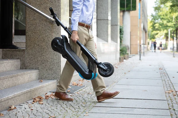 Man Draagt Scooter Van Het Werk Lopen Uit Kantoorgebouw — Stockfoto