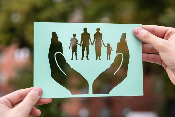 Hands Holding Paper Cutout Hands Protecting Family Outdoors — Stock Photo, Image