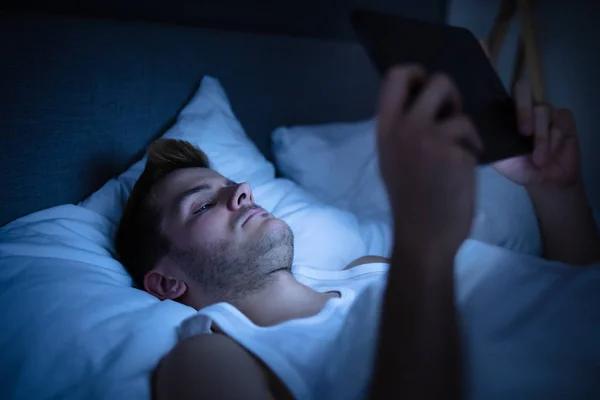在床上睡觉的人 晚上有数码记事本 — 图库照片