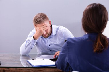 Ofisteki görüşmede kafasını tutan stresli genç iş adamı