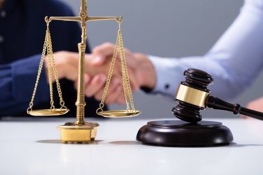 Tahta Gavel ve Altın Adalet Ölçeği Müşteri ve Avukatın önünde Tokalaşıyor