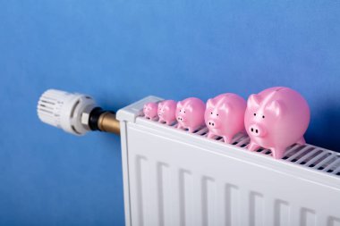 Radyatör üzerinde bir satır tutulan Pembe Piggy Bankalar Close-up