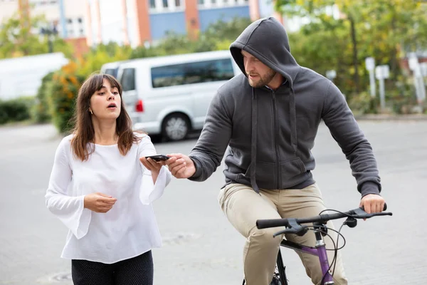 Ladrón Masculino Montando Bicicleta Arrebatando Teléfono Móvil Mano Mujer Caminando —  Fotos de Stock