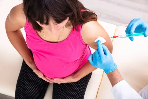 戴蓝色手套的医生在诊所为年轻孕妇接种疫苗的特写 — 图库照片