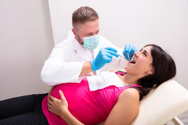 Мужчина Дантист Лечит Зубы Молодой Беременной Пациентки Лежащей Клинике — стоковое фото