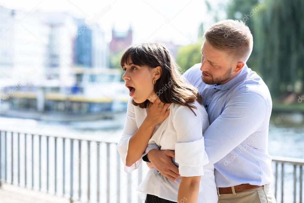 Man Helping Choking Woman To Expel A Trapped Object From Airway. Heimlich Maneuver