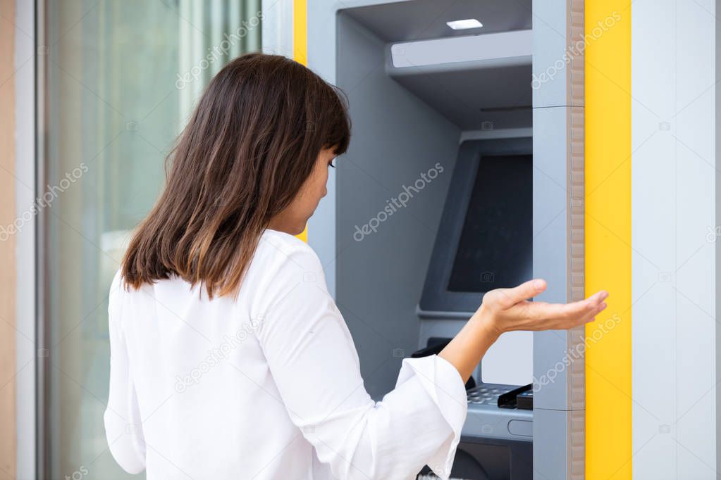 Close-up Of Disappointed Young Woman Looking At ATM Bank Machine After Checking The Account Balance