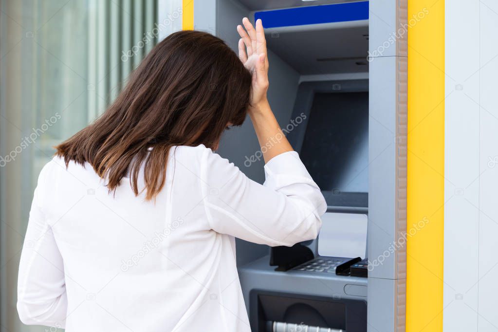 Close-up Of Disappointed Young Woman Looking At ATM Bank Machine After Checking The Account Balance