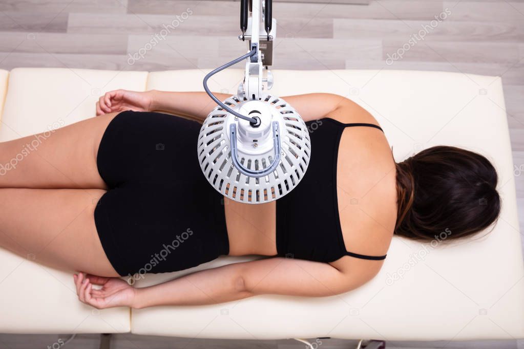 Medicinal Infrared Radiating Treatment On Woman's Back Lying On Bed In Medical Clinic