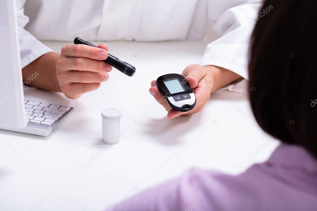 Doctor Showing Lancet Pen And Digital Glucometer To Woman For Checking Blood Sugar Level