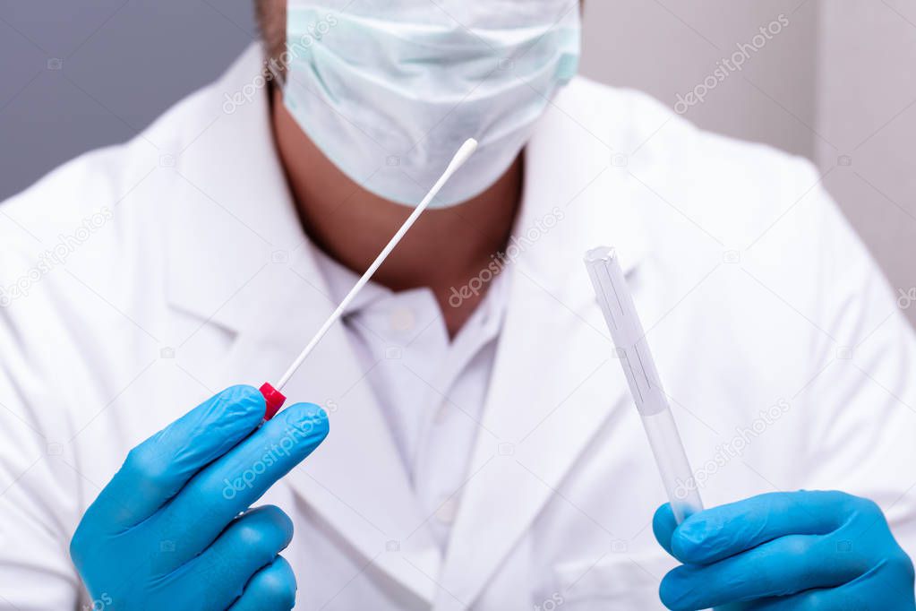 Male Doctor Wearing Blue Gloves Holding Cotton Swab And DNA Test Tube