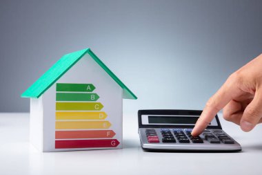 Masadaki Hesap Makinesini kullanarak, Minyatür Ev Enerji Verimliliği Oranını Gösteriyor