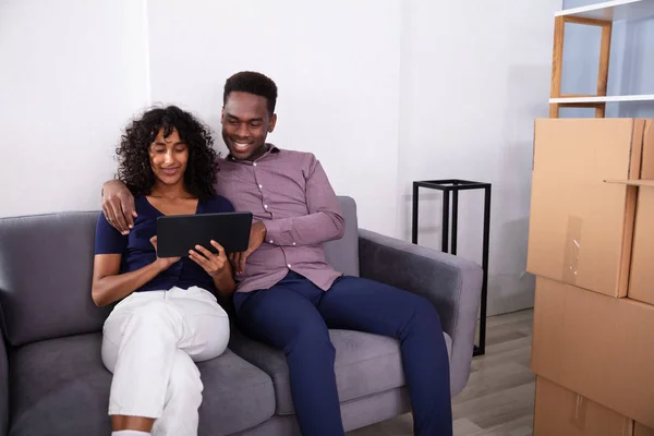 一对年轻夫妇坐在沙发上 在他们的新家里使用平板电脑 — 图库照片