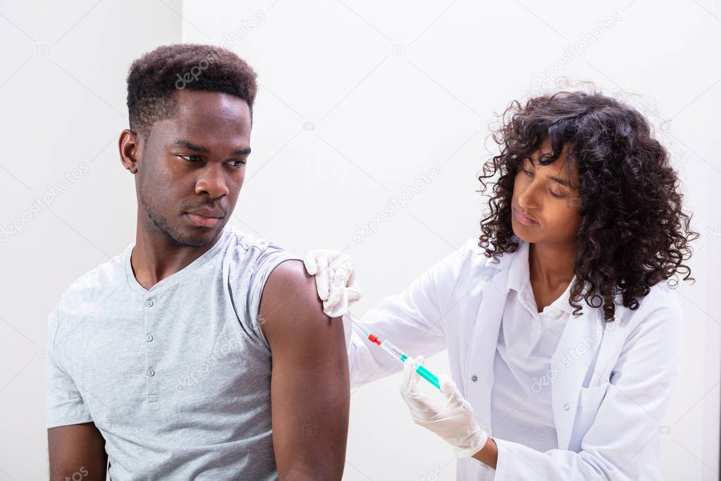 Close-up Of Doctor Injecting Vaccine Into Patients Arm With Syringe