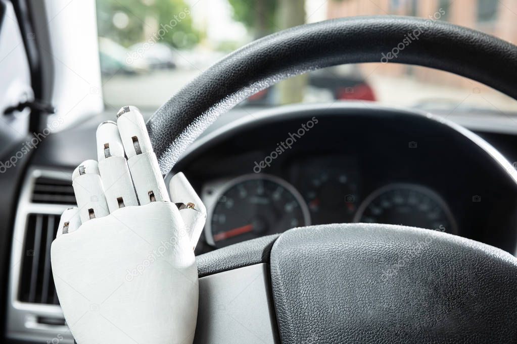 Close-up Of Robotic Hands On Car's Steering Wheel