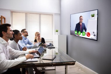 bilgisayar ekranına bakarak bir konferans odasında oturup iş adamları