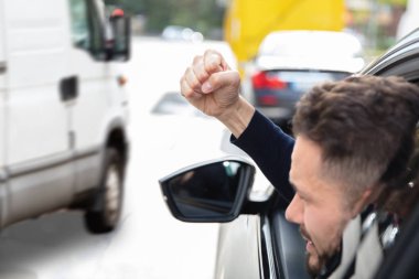 Young Man Looking Out From Car Through Window And Clenching His Fist