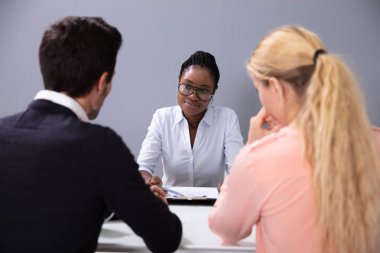 Evlat edinme ajansındaki görüşmede oturan ve konuşan çift.