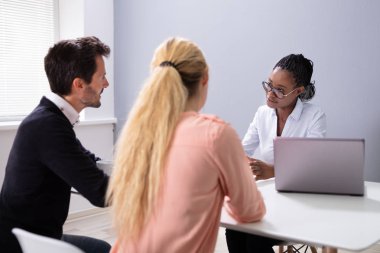 Evlat edinme ajansındaki görüşmede oturan ve konuşan çift.