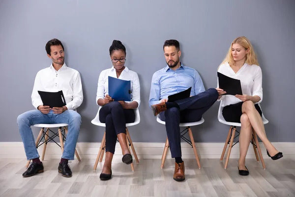Multiethnische Geschäftsleute Sitzen Auf Stühlen Reihe Und Warten Vor Grauer — Stockfoto