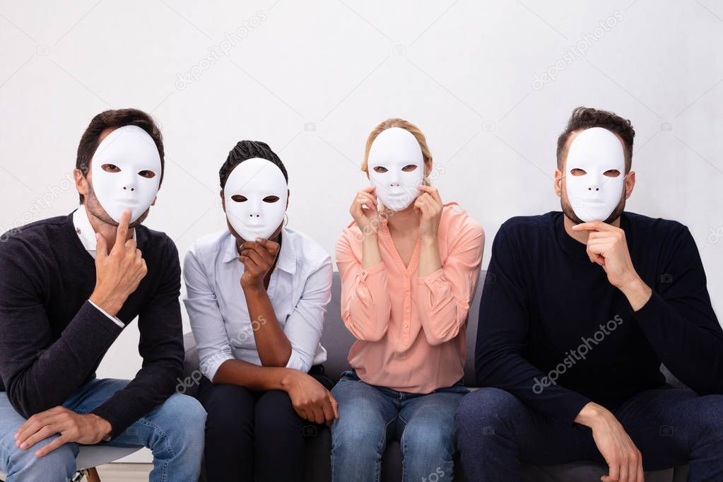 Group Of People Standing Together Covering His Face With White Masks