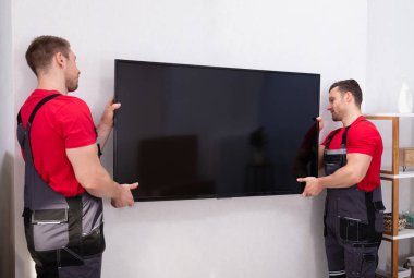 Nakliyeciler oturma odasındaki büyük LCD Televizyonunu tamir ediyor.