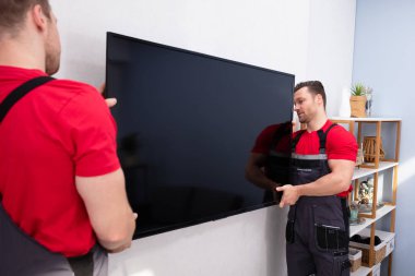 Nakliyeciler oturma odasındaki büyük LCD Televizyonunu tamir ediyor.