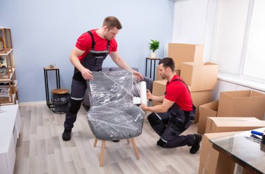 İki Genç Erkek Nakliyeci Oturma Odasında Plastik Paketlenmiş Mobilya Paketi